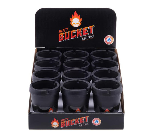 A black display box of Butt Bucket Ashtray, showing 12 black ashtrays arranged in a 3x4 grid. The display box features the Butt Bucket logo with a skull and flames.